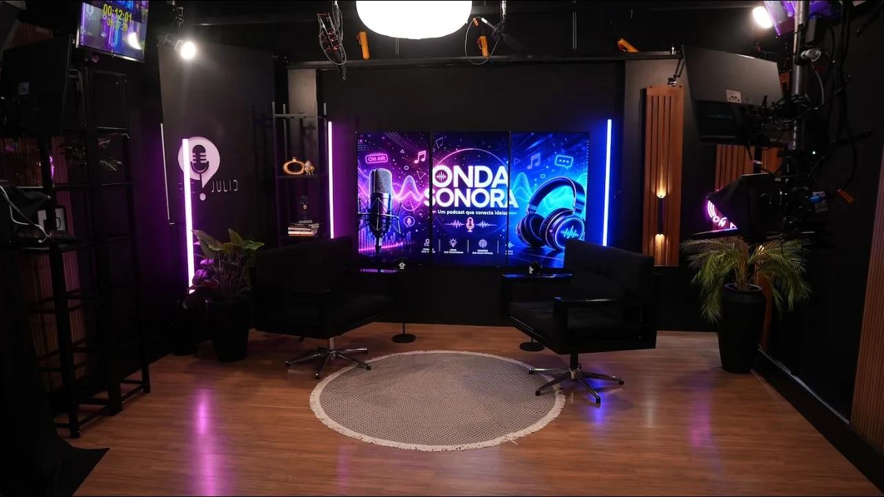 Cenário do Estúdio VIP iluminado por LED e neon, com poltronas e painel de vídeo