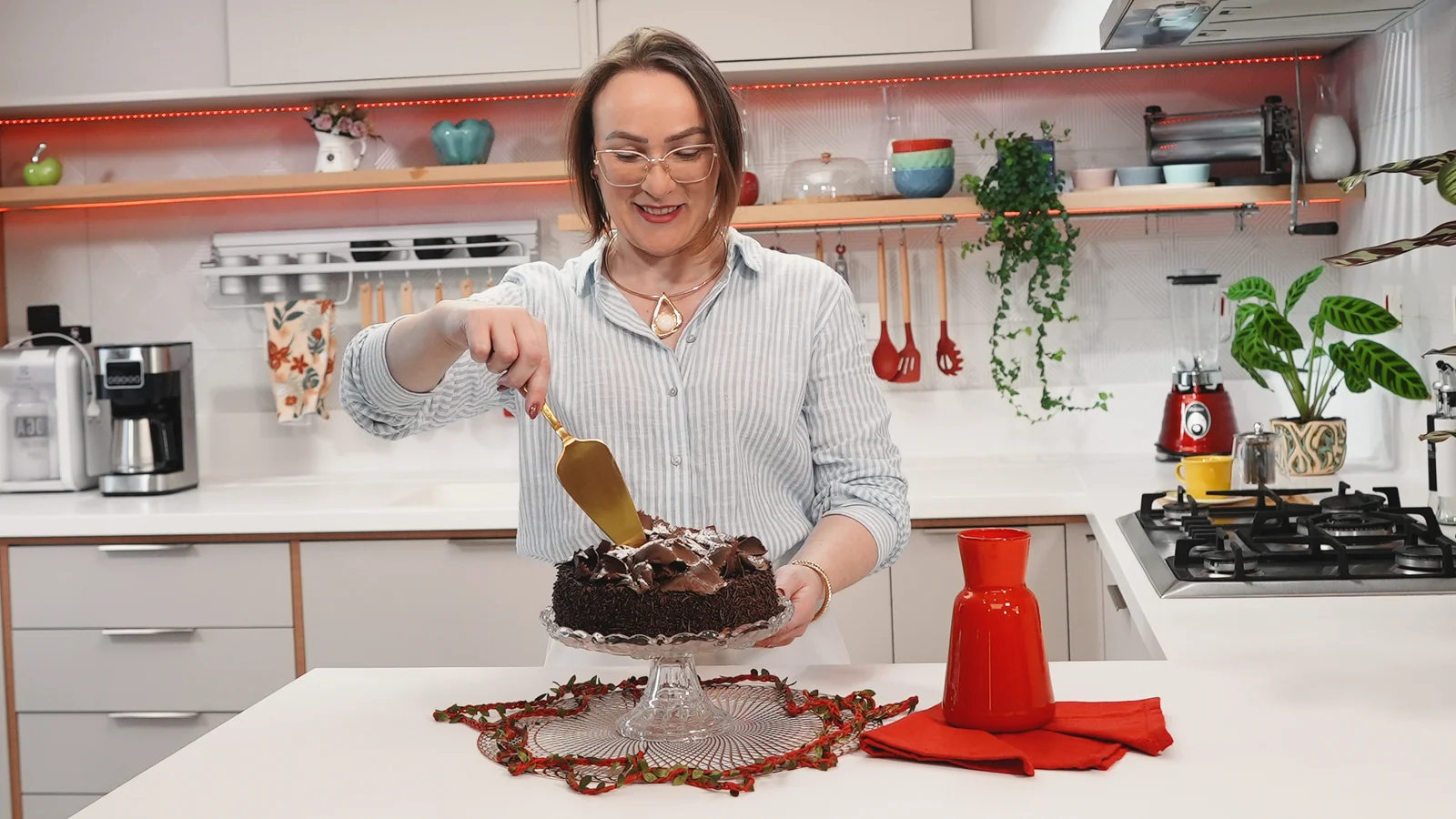 Espaço gourmet do Estúdio Master com bancadas brancas, cooktop e prateleiras iluminadas durante gravação de conteúdo gastronômico